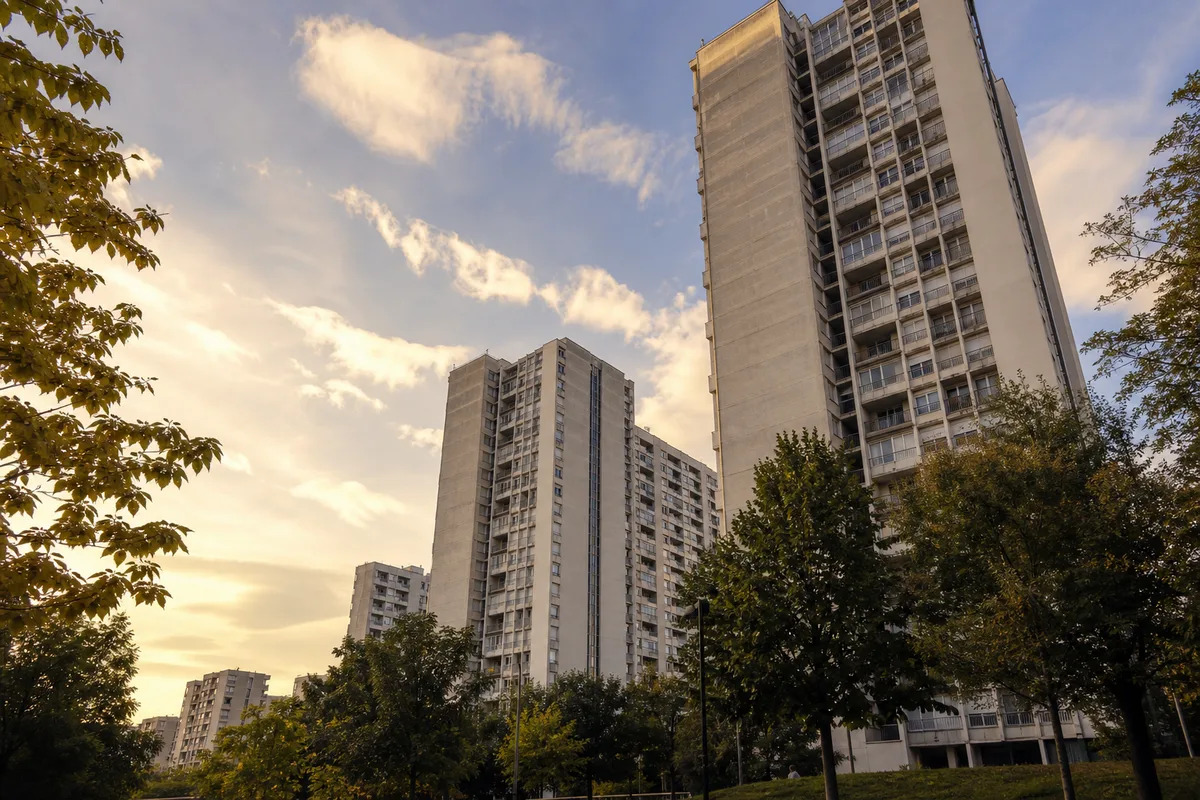 Tours et barres d&rsquo;habitation d&rsquo;un grand ensemble vaudais sous une lumière de fin de journée, colonnes techniques apparentes en façade